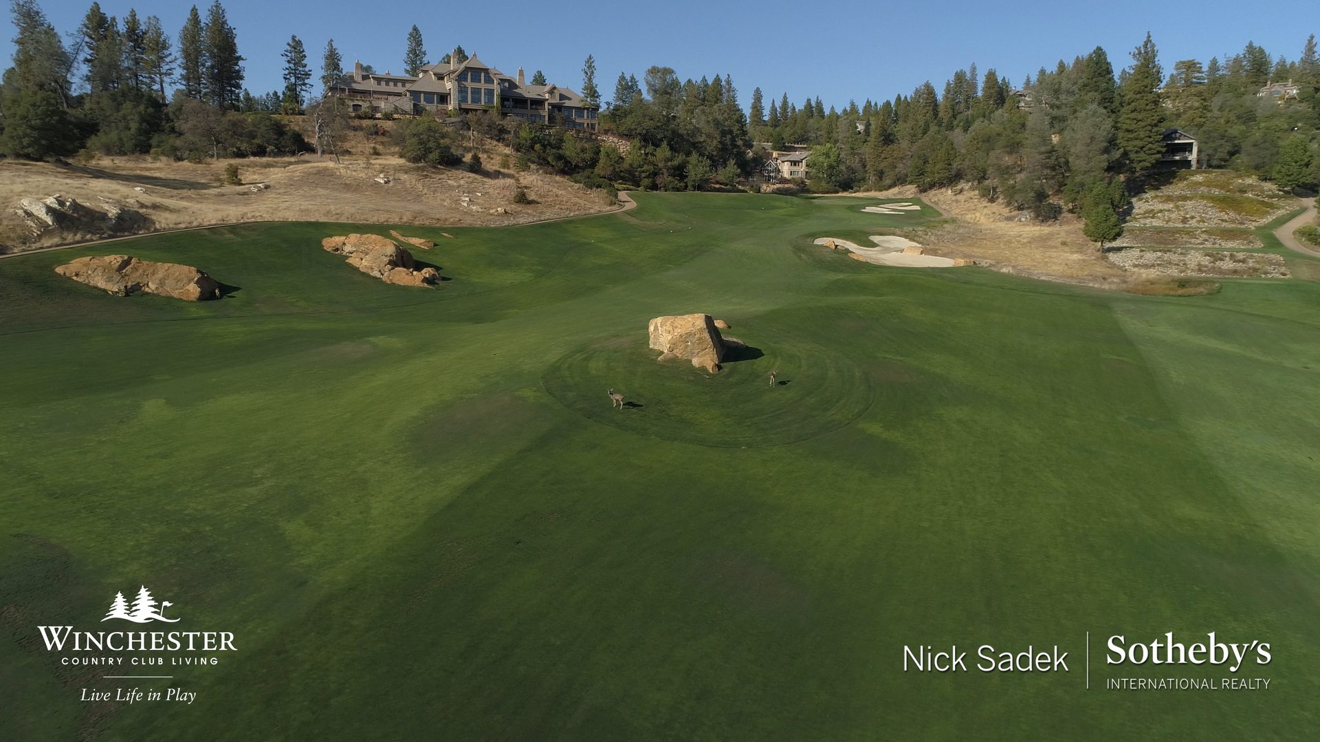 Golf fairway with rocks, trees, and distant clubhouse